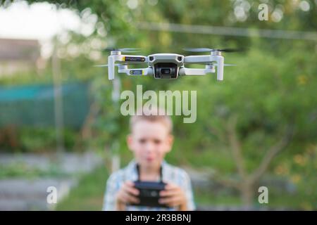 Kid flying drone. Boy operate drones. Child Operating Quadcopter. Little Pilot Using Drone Remote Co Stock Photo