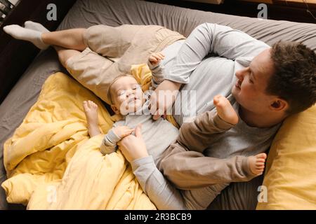 Father playing with son on bed at home Stock Photo