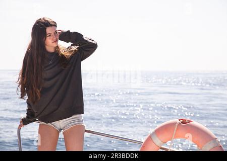 Teenage girl with hand in hair on boat sailing in sea Stock Photo