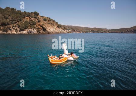 Men enjoying vacation floating on air mattress in sea Stock Photo