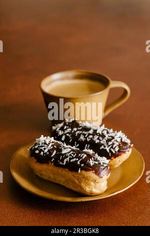 Coconut eclairs and cup of coffee Stock Photo