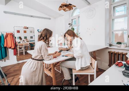 Fashion designers discussing over smart phone at workshop Stock Photo