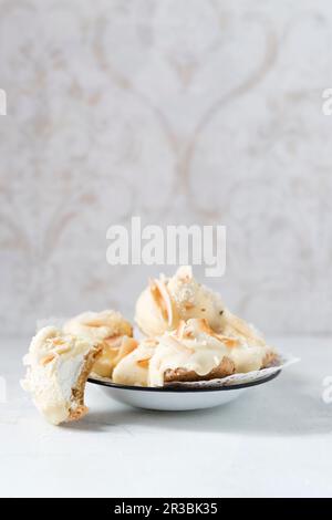 Homemade foam kisses with white chocolate and coconut shavings on a biscuit base Stock Photo