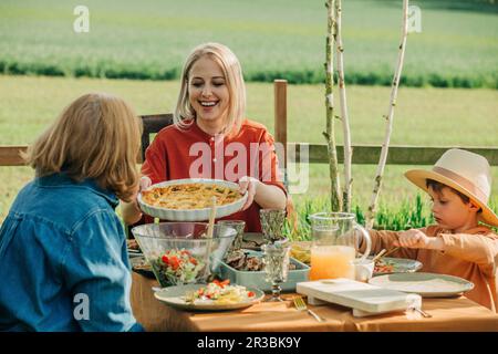 Happy family having healthy lunch at dining table in back yard Stock Photo