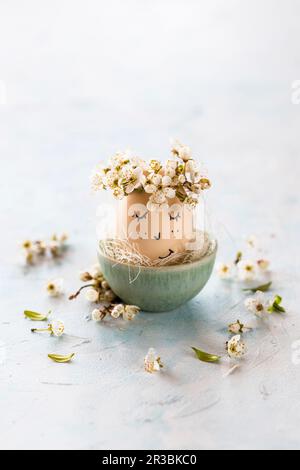 An Easter egg with a face and flower petals Stock Photo
