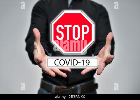 Man is holding a Stop sign, Stop COVID-19 Stock Photo