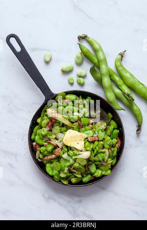 Fried broad beans with bacon in a pan Stock Photo