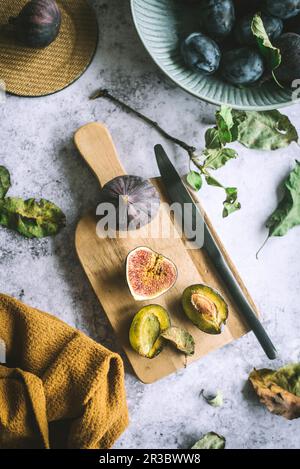 Fresh figs and plums on cutting board Stock Photo