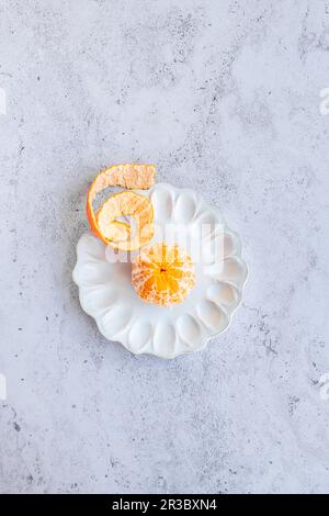 Peeled honey gold tangerine on a decorative ceramic plate Stock Photo