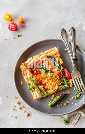 Tart on puff pastry with asparagus, cherry tomatoes, and Parmesan crumble Stock Photo