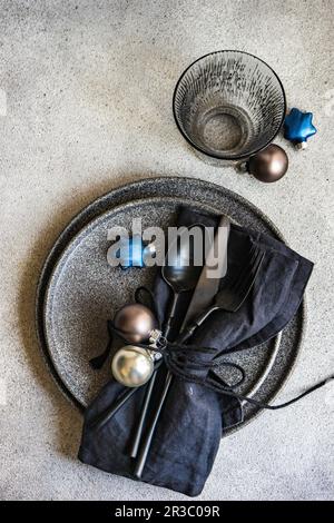 Minimalistic table setting with black stoneware and Christmas decoration on grey concrete background Stock Photo