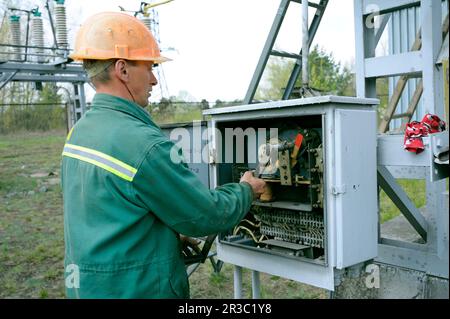 At the power substation. Worker checking connections on the electric board turning start tumbler Stock Photo