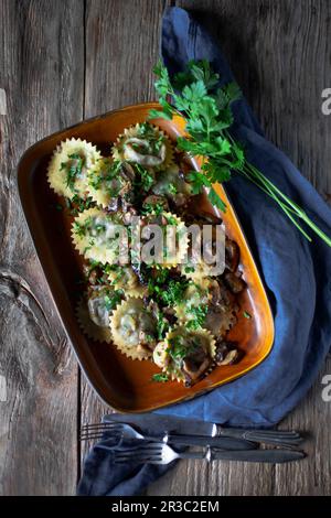 Round ravioli with mushroom sauce and herbs Stock Photo