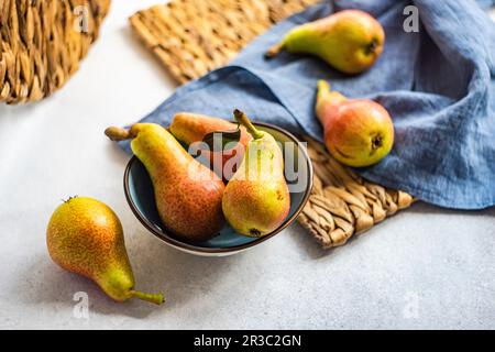 Organic ripe pears in ceramic bowl on rustic table Stock Photo
