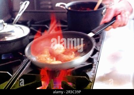 Mushroom caps being flambéed with cognac in a commercial kitchen setting Stock Photo