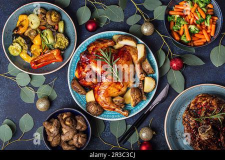 Christmas evening celebrating table with baked chicken, roasted ham, vegetables, decorated with eucalyptus branches Stock Photo