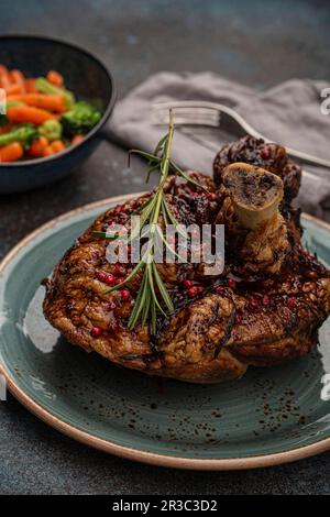Delicious roasted pork knuckle with glazed brown crispy skin, red pepper berries and rosemary Stock Photo
