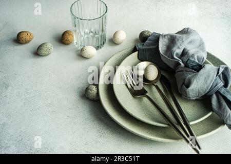 Place setting for Easter festive dinner with eggs on concrete background Stock Photo