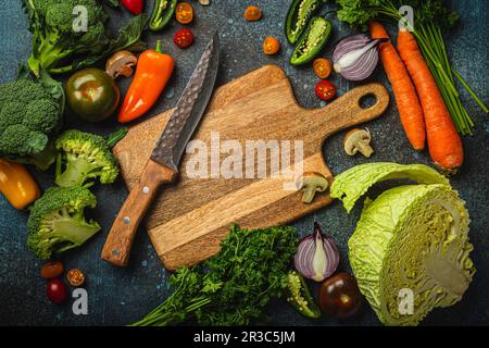 Assorted fresh vegetables on rustic concrete table with wooden cutting board Stock Photo