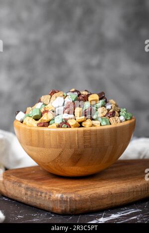 Colorful chocolate candy stones. Stone chocolate dragee in wooden bowl on dark background. Small multi-colored candies. Close up Stock Photo