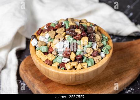 Colorful chocolate candy stones. Stone chocolate dragee in wooden bowl on dark background. Small multi-colored candies. Close up Stock Photo