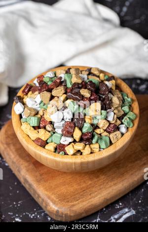 Colorful chocolate candy stones. Stone chocolate dragee in wooden bowl on dark background. Small multi-colored candies Stock Photo