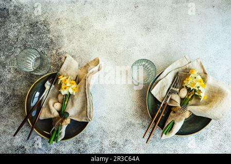 Minimalistic table setting for easter festive dinner decorated with daffodil flowers Stock Photo