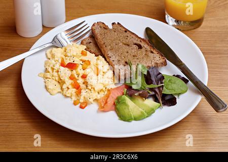 Scrambled eggs, smoked salmon, avocado, brown toast and salad Stock Photo