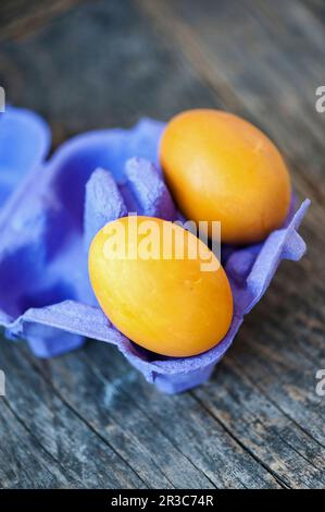 Yellow Easter eggs in a purple cardboard Stock Photo