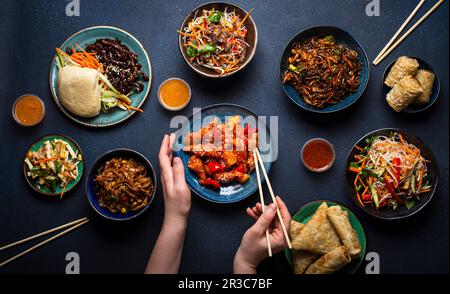 Set of Chinese dishes on table, female hands holding chopsticks Stock Photo
