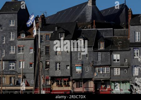 In Honfleur in Calvados, Normandy, France, tile-hung townhouses lining the Quai Sainte Catherine are dominated by the roof of an historic church, the Église Sainte-Catherine, which rises behind. This image was captured from the other side of the Vieux Bassin (Old Basin, Harbour or Dock), begun in 1668 as a new harbour for Honfleur. Stock Photo