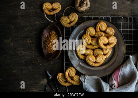 Traditional Puff pastry spiral biscuits known as a pig s ears on plate with sugar Stock Photo