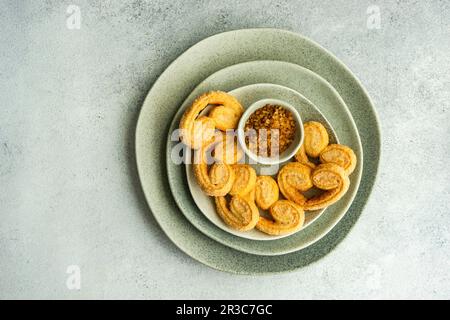 Traditional Puff pastry spiral biscuits known as a pig s ears on plate with sugar Stock Photo
