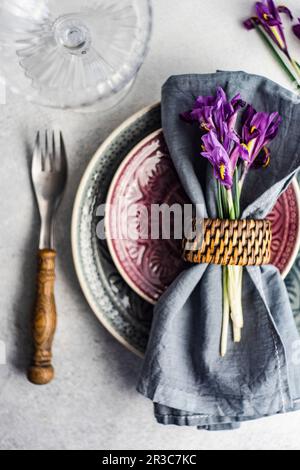 Spring floral table setting decorated with wild purple iris flowers on concrete table Stock Photo