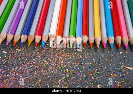Close up shot of colored pencil crayons and pencil crayons shavings on dark background. Sharpened co Stock Photo