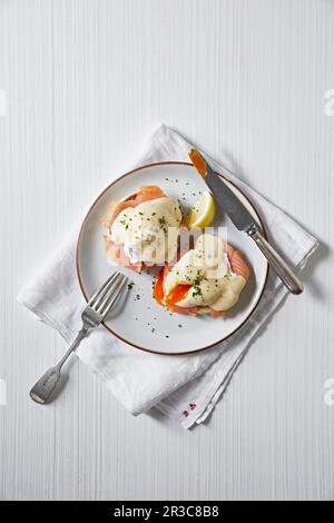Poached eggs with runny yolks served with smoked salmon and a hollandaise sauce on muffins Stock Photo