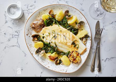 Lemon sole with clams, potatoes and green vegetables Stock Photo