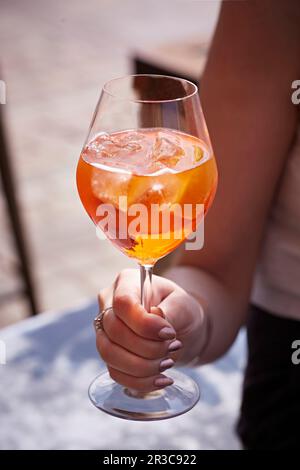 Hand holding stemmed glass with Aperol Spritz Stock Photo