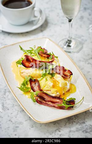 Poached eggs with bacon and hollandaise sauce on muffins Stock Photo