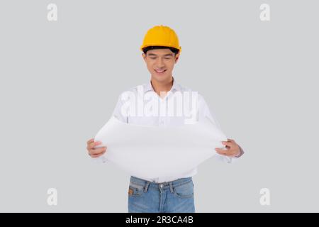 Portrait young asian man is engineer wearing helmet holding and looking blueprint with confident isolated on white background, handsome male is archit Stock Photo