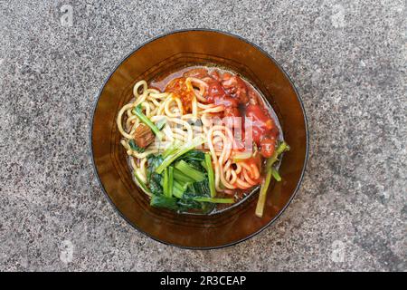 A serving of chicken noodles in a bowl is seen from the top angle Stock Photo