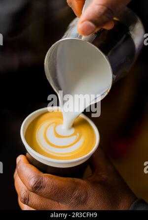 African Coffee Barista pouring a leaf shape with milk foam Stock Photo