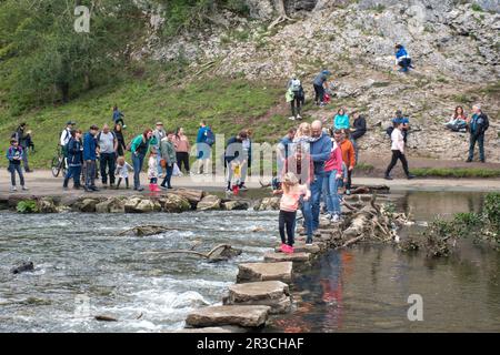 Tourists crossing  the famous stepping stones at Dove Dale's stepping stones Stock Photo