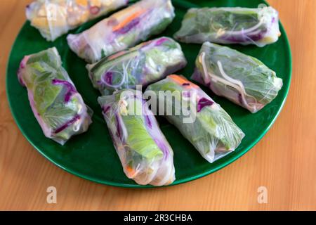 Fresh Spring Rolls on large green plate, view from above. Raw vegan dish, Vietnamese appetizer or main course, colourful vegetables wrapped in rice pa Stock Photo