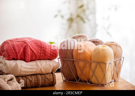 Cozy knitted sweaters with balls of yarn in the living room Stock Photo
