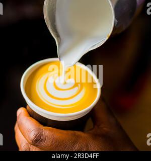 African Coffee Barista pouring a leaf shape with milk foam Stock Photo