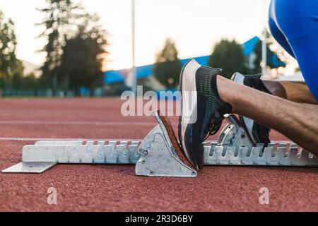 Male sprinter feet, in black sneakers, pushing off from the starting block, and start a race, close up shot. Stock Photo