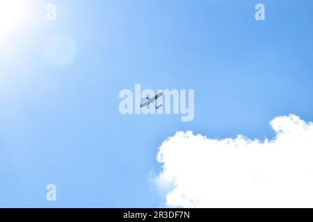 Airplane flying in the blue sky on background of white clouds, rear view. Twin-engine commercial plane during the turn, vacation Stock Photo