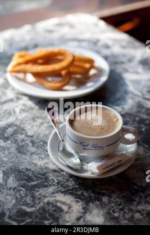 A café con leche (coffee with milk) and churros (at the famous Café Gijón. Madrid, Spain. Stock Photo