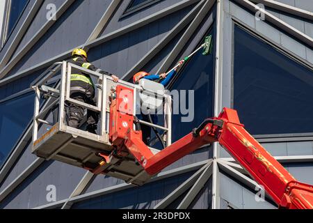 Window cleaner cleaning modern office building windows on articulating boom lift in Rotermanni Quarter of Tallinn, Estonia Stock Photo